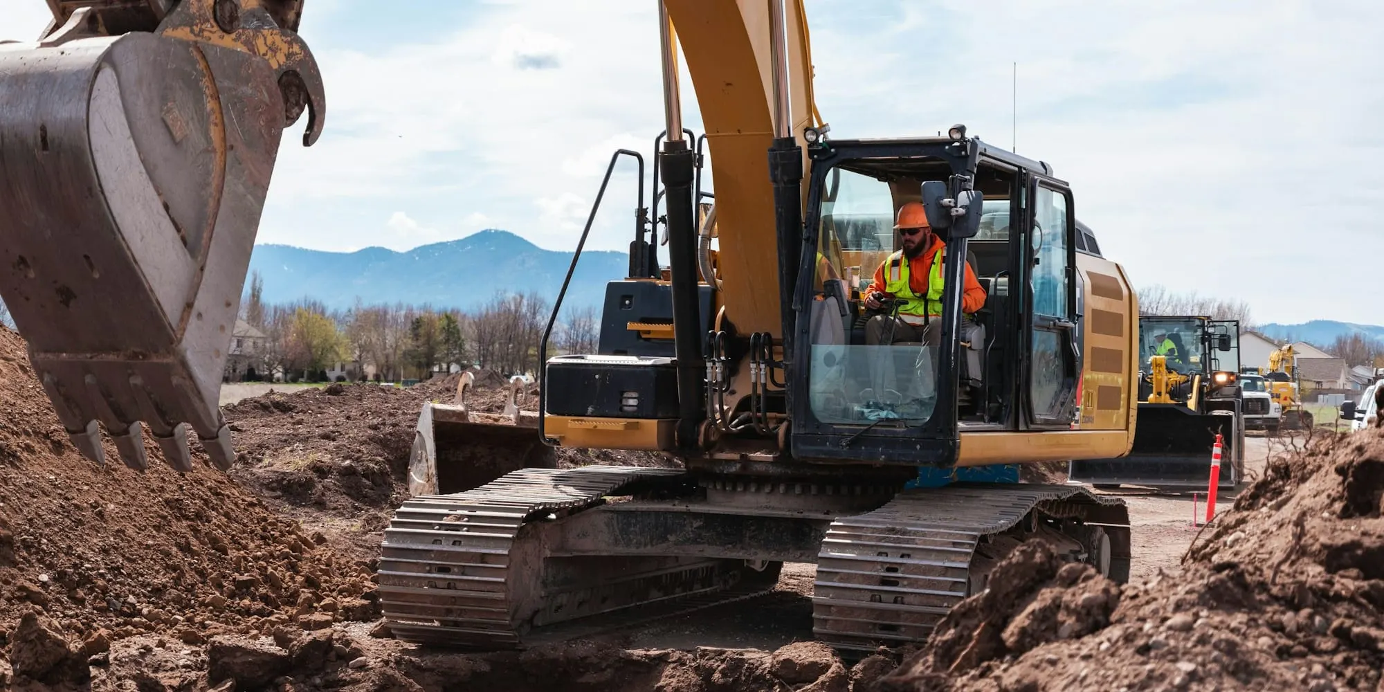 Yellow excavator with its operator digging on a mountain job site